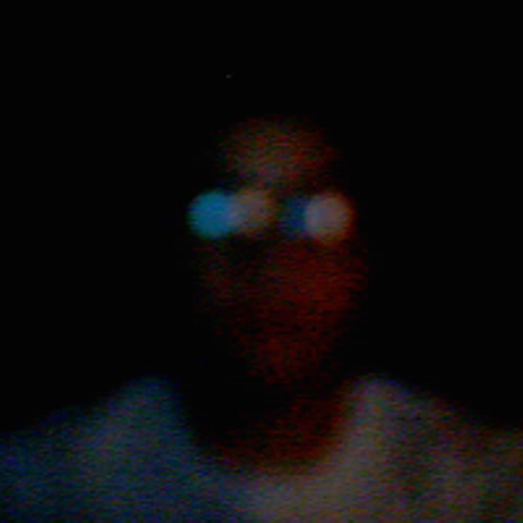 Man's headshot with a dark background and dark collared shirt